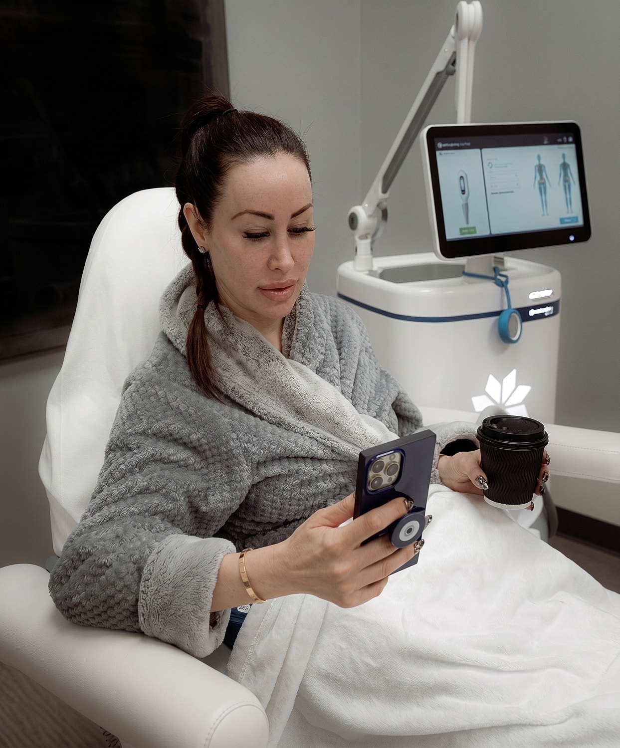 Woman relaxing with phone and coffee in spa.