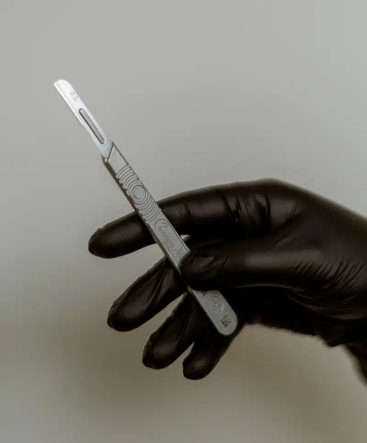 Hand holding a surgical scalpel with gloves.