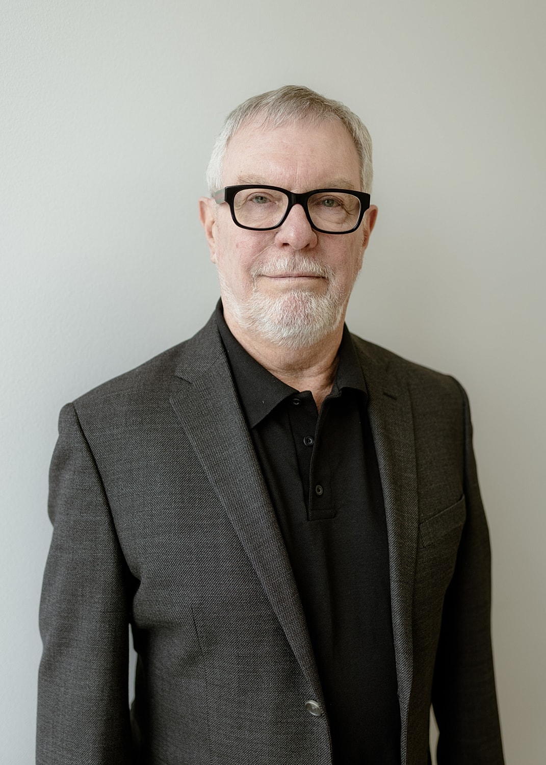 Senior man in a suit against a plain background.