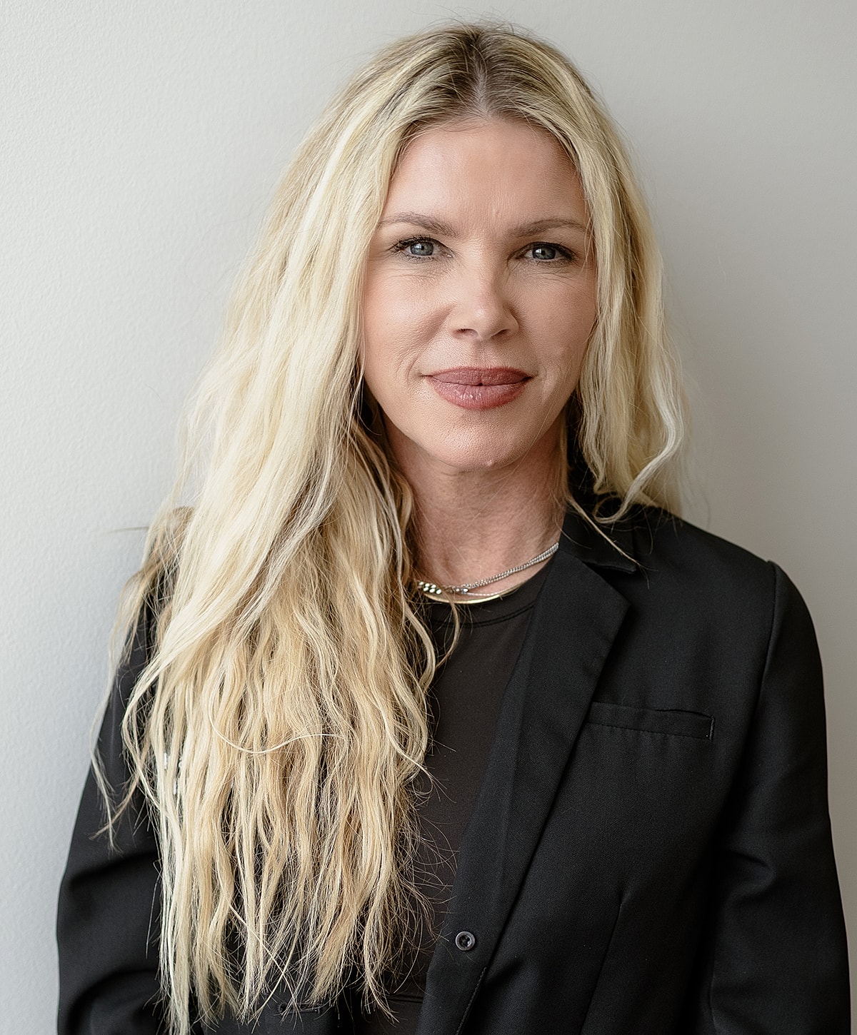 Woman with long blonde hair against a wall.