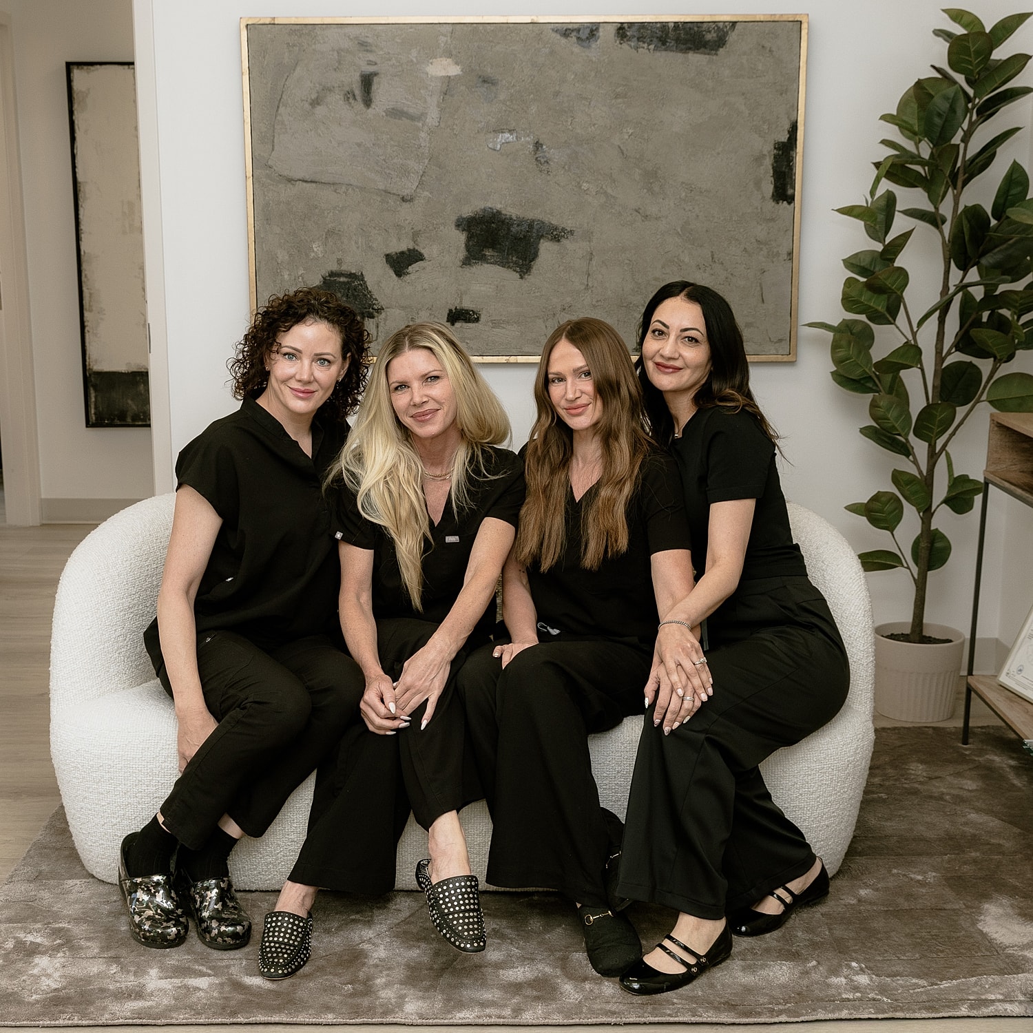 Four women posing together on a sofa.