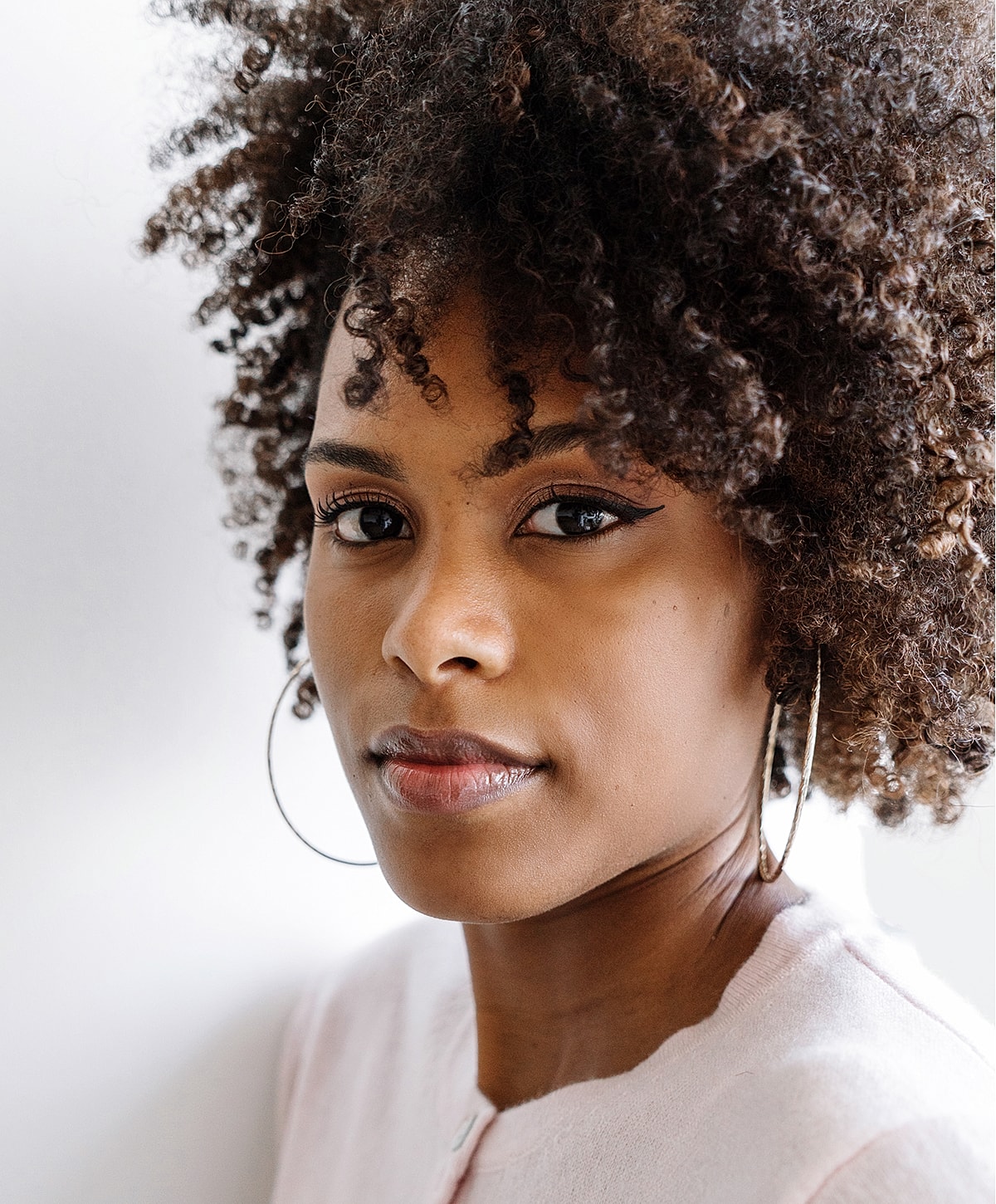 Woman with curly hair and hoop earrings.