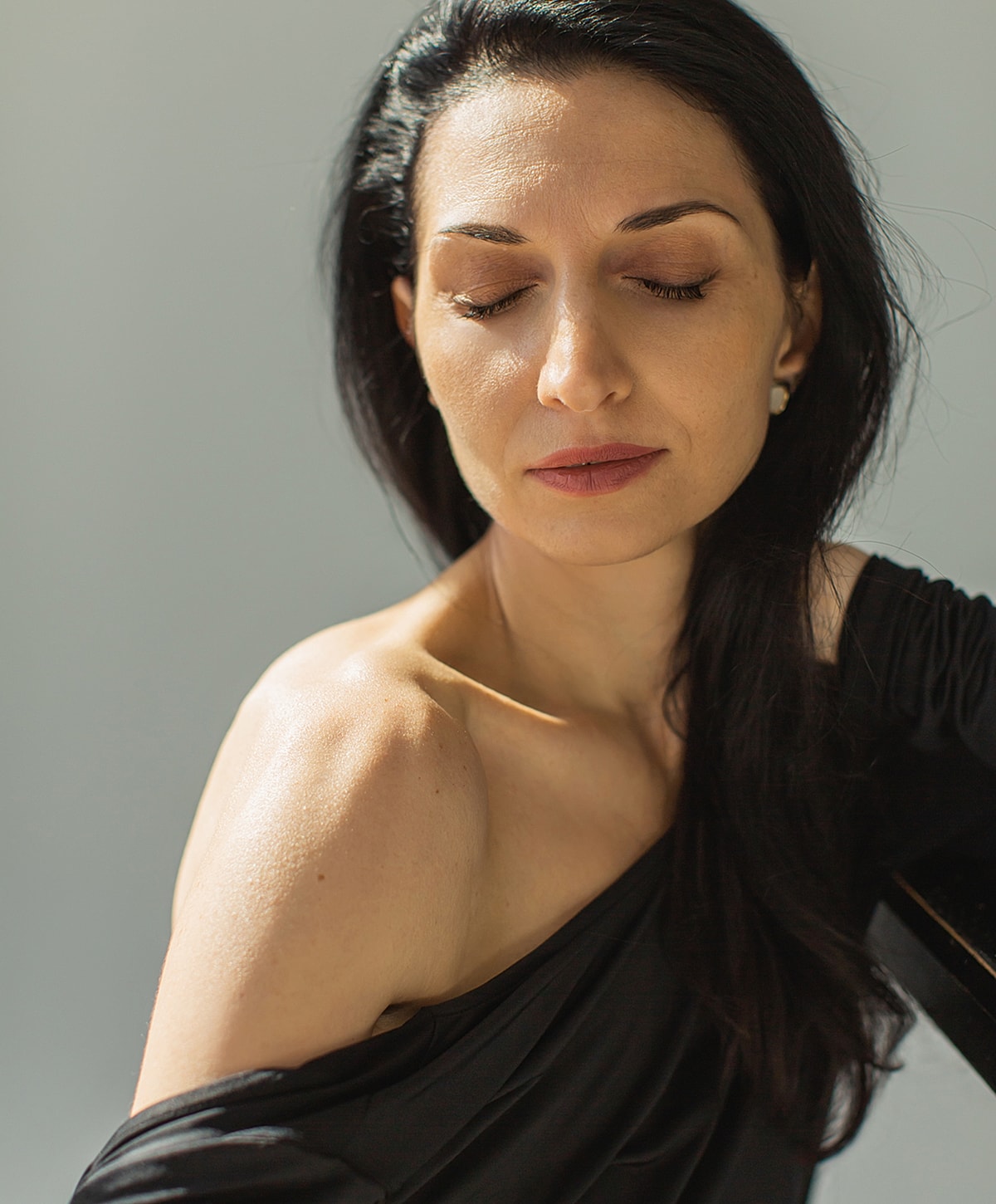 Woman with eyes closed, illuminated by sunlight.