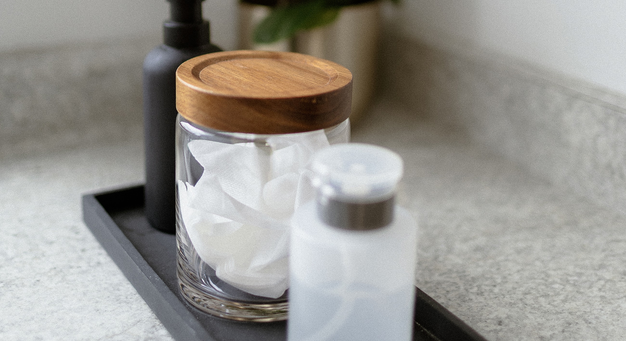 Bathroom countertop with skincare products and cotton pads.