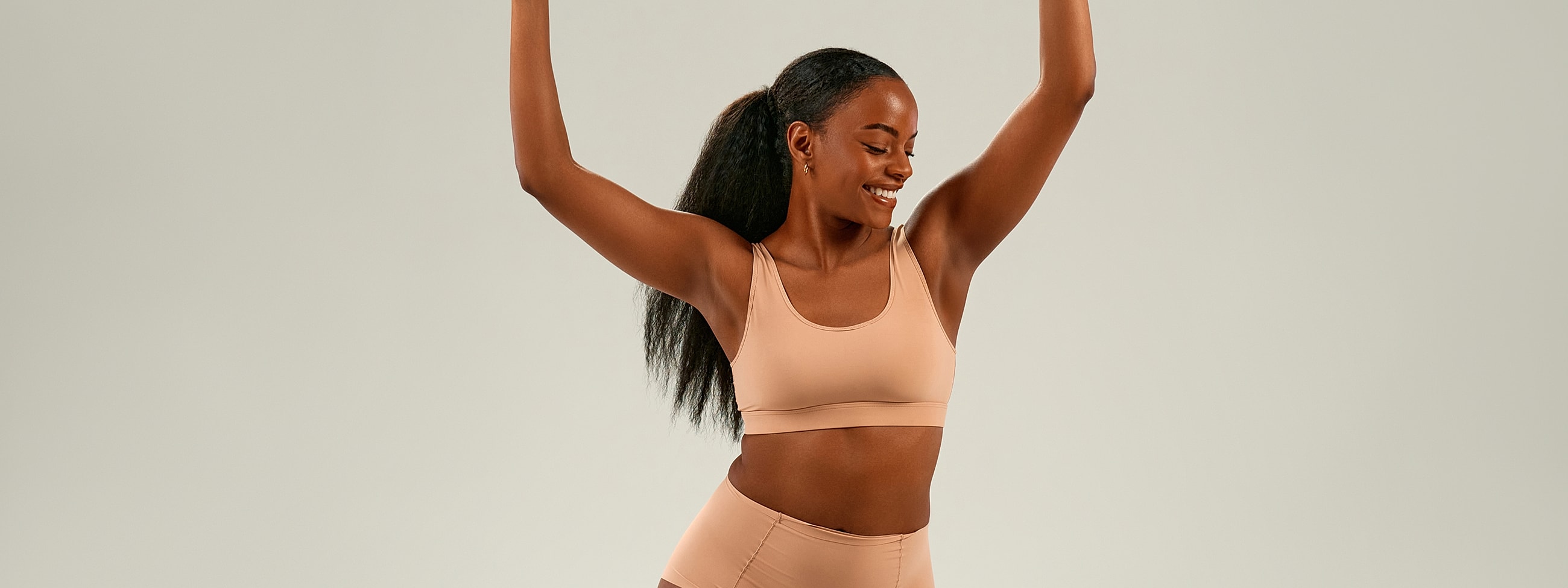 Woman in activewear celebrating with raised arms.