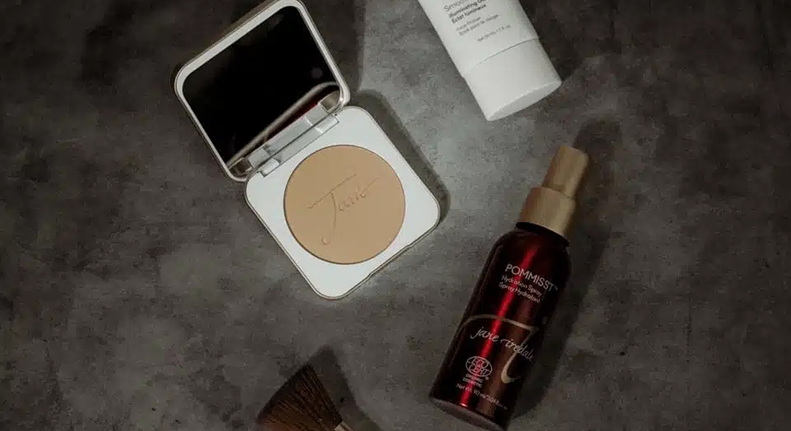 Makeup products arranged on a textured surface.
